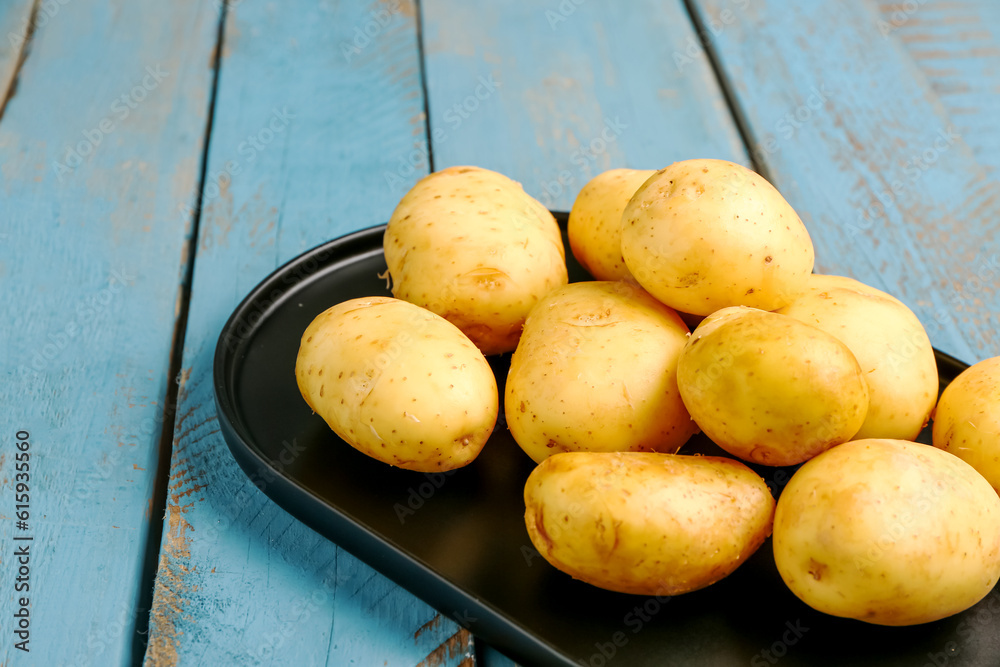 Tray with raw baby potatoes on blue wooden background