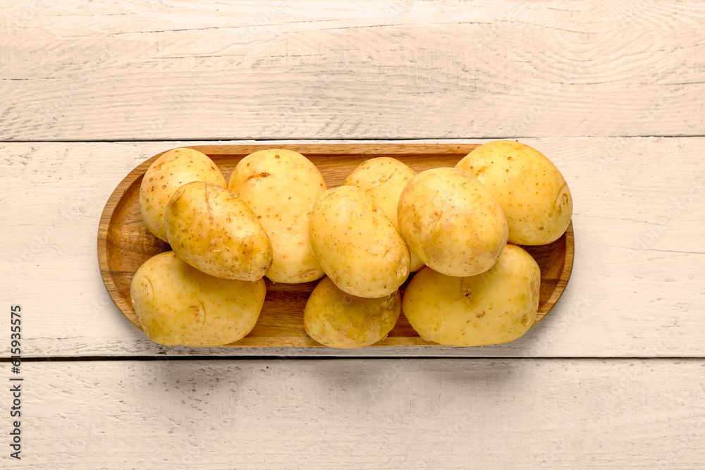 Tray with raw baby potatoes on white wooden background