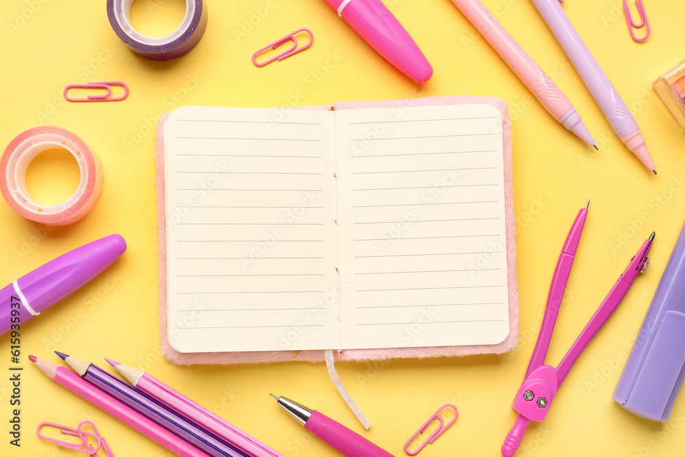 Notebook with different school stationery on yellow background