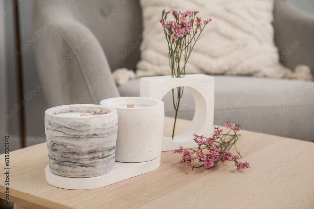 Interior of light living room with candles and flowers on table, closeup