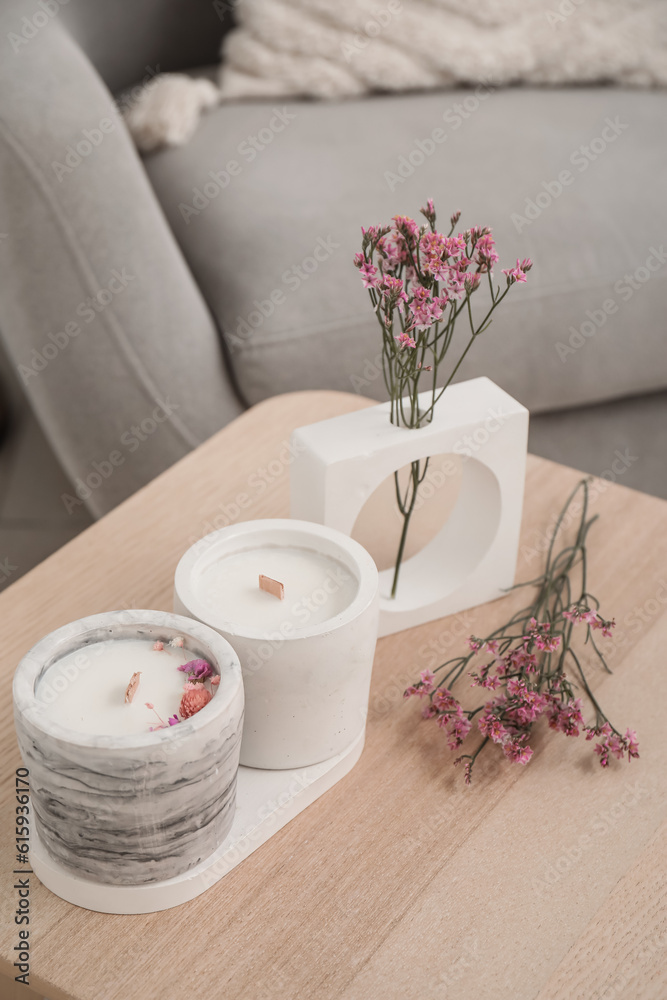 Interior of light living room with candles and flowers on table, closeup