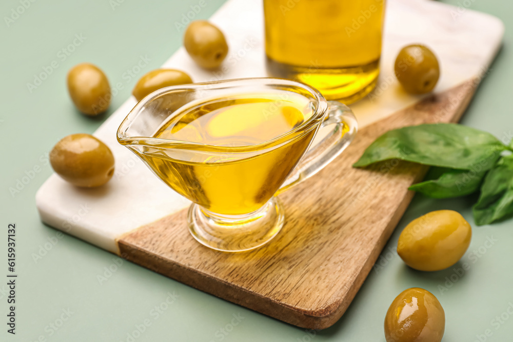 Gravy boat with fresh olive oil on green background