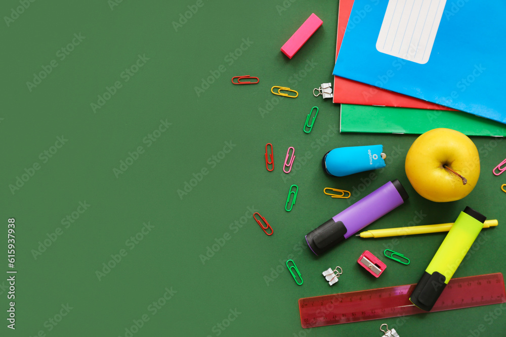 Fresh apple with different stationery on green background