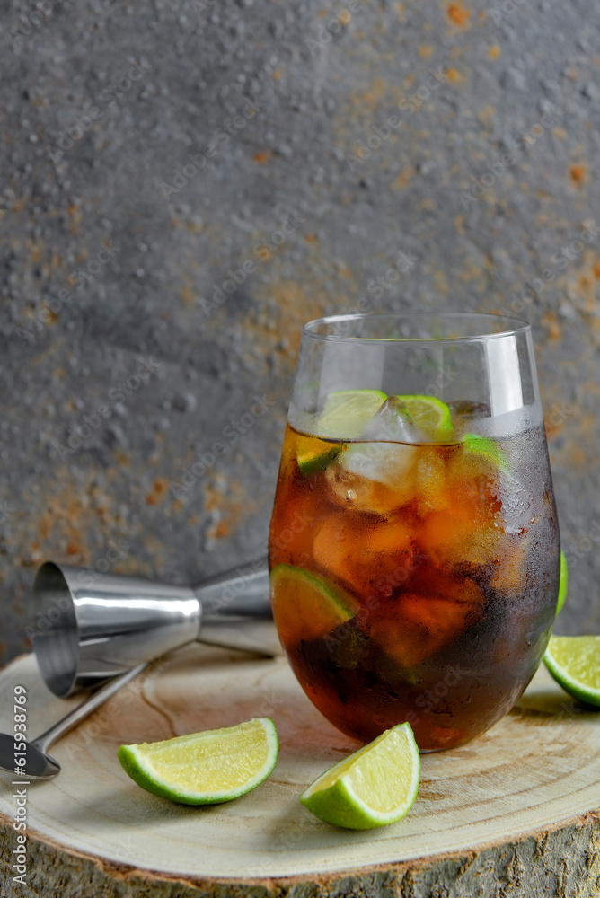 Glass of cold Cuba Libre cocktail on wooden table