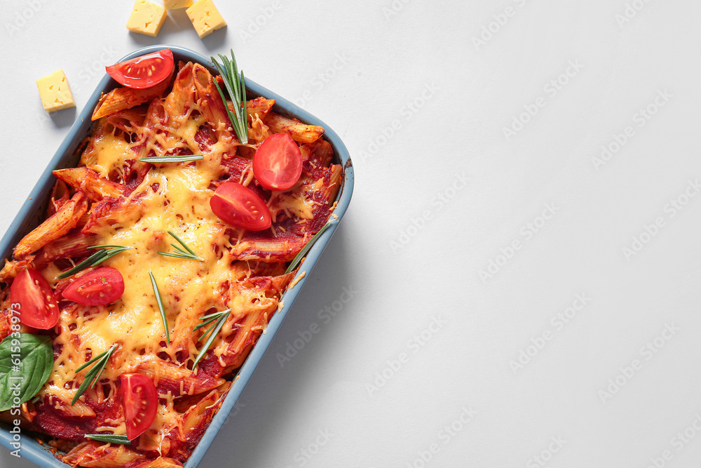 Baking dish of pasta with tomato sauce and cheese on grey background