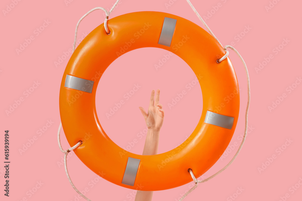 Female lifeguard with ring buoy on pink background