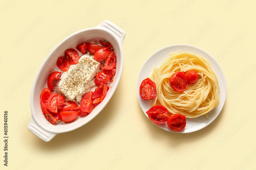 Baking dish with tomatoes, feta cheese and pasta on yellow background