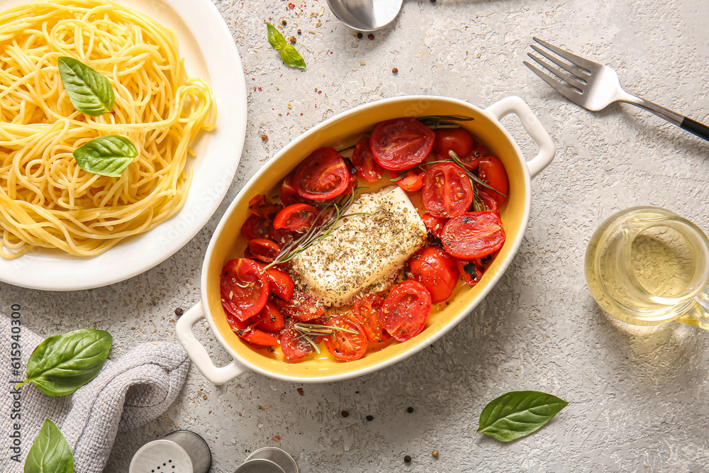 Baking dish with tasty tomatoes, feta cheese and pasta on grey background