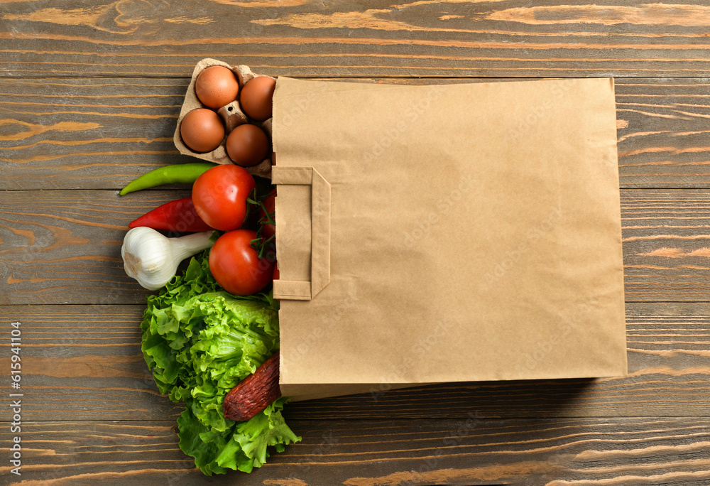 Paper bag with different products on wooden background