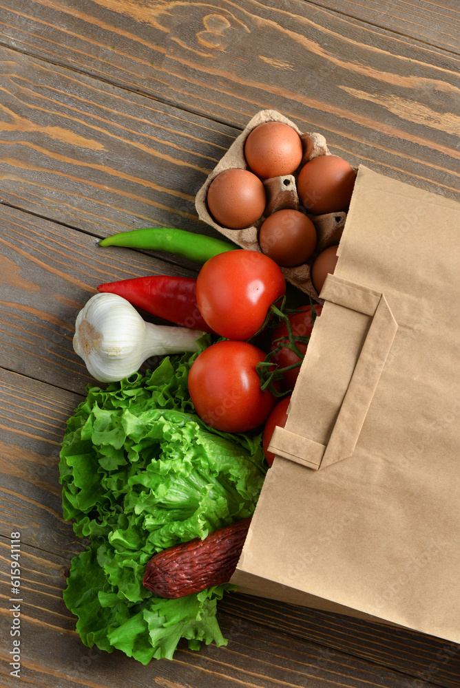 Paper bag with different products on wooden background