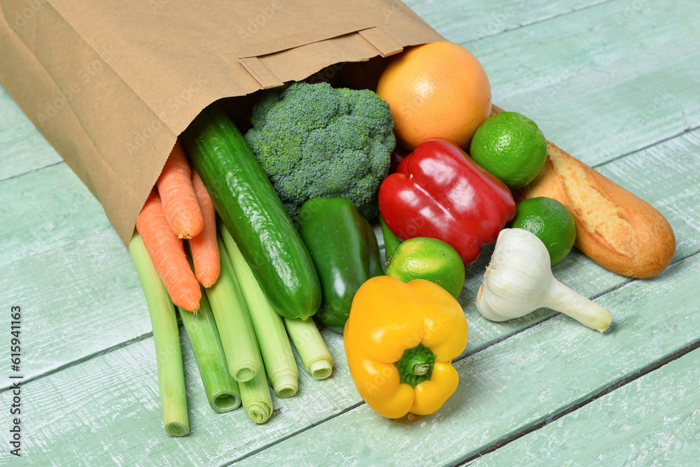 Paper bag with different products on green wooden background