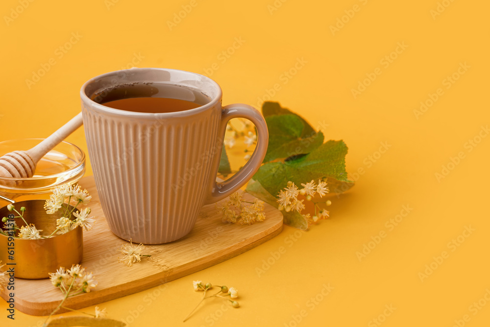 Cup of linden tea and bowl with honey on orange background