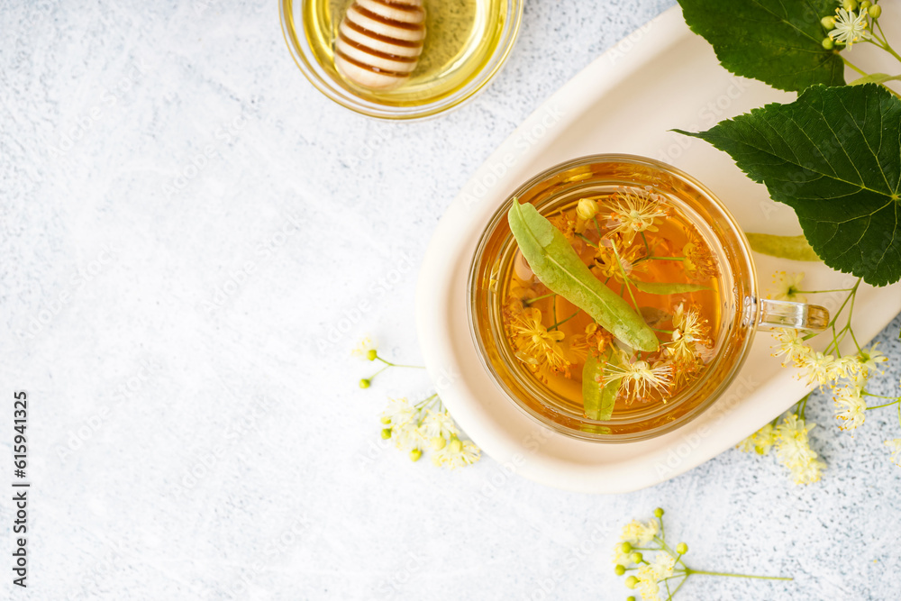 Glass cup of linden tea and bowl with honey on white background