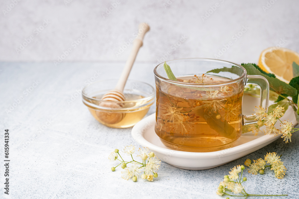 Glass cup of linden tea and bowl with honey on white background