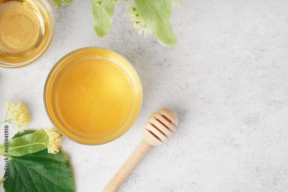 Glass bowl with linden honey and dipper on light background