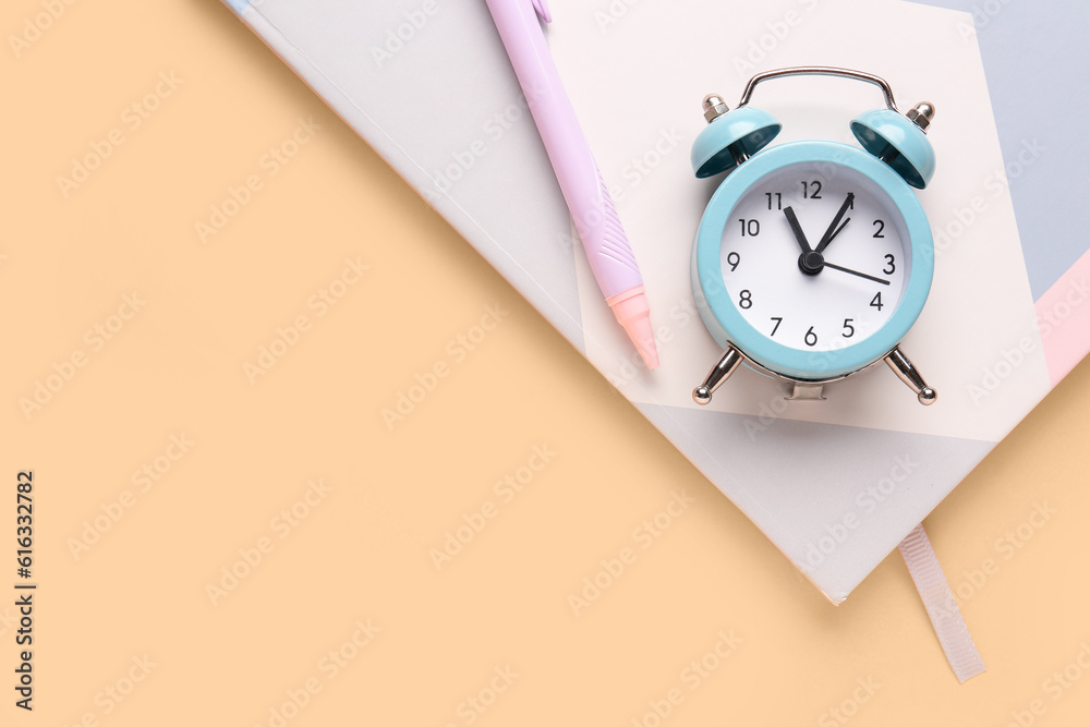 Notebook, pen and alarm clock on color background