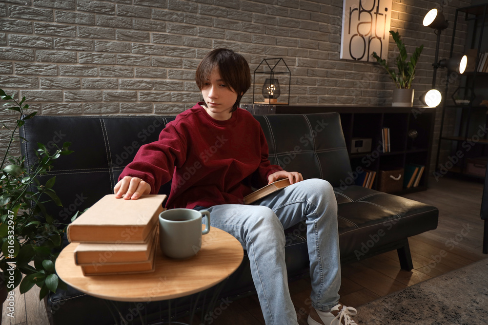 Teenage boy taking book from table at home late in evening