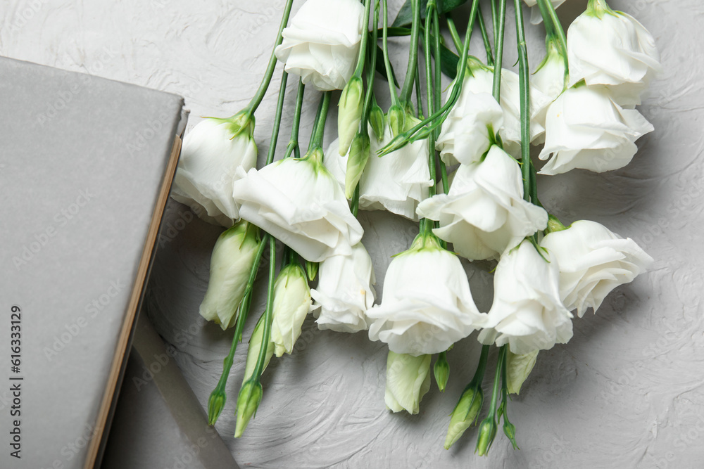 Beautiful eustoma flowers and books on light background, closeup