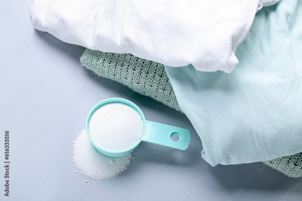 Laundry detergent with clothes on light background, closeup