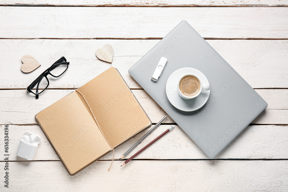 Composition with notebook, laptop, cup of coffee and glasses on white wooden table