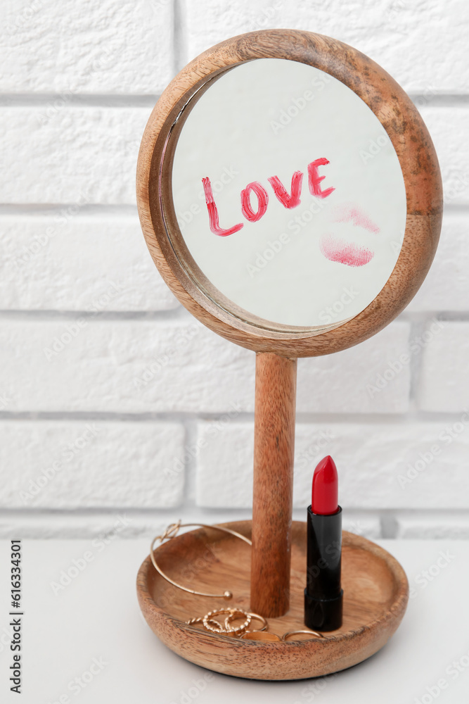 Word LOVE written with red lipstick on mirror