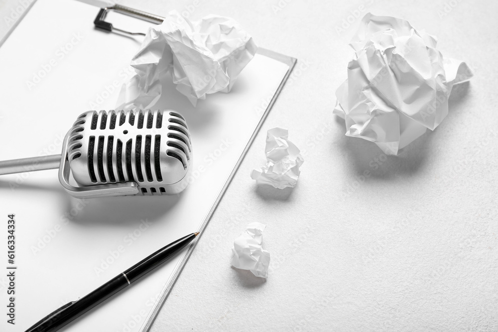 Clipboard with microphone and crumpled paper on white background, closeup