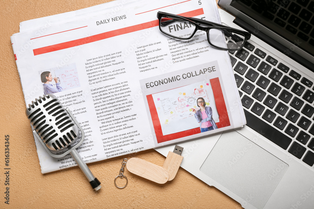 Newspaper with microphone, eyeglasses, USB flash drive and laptop on beige background