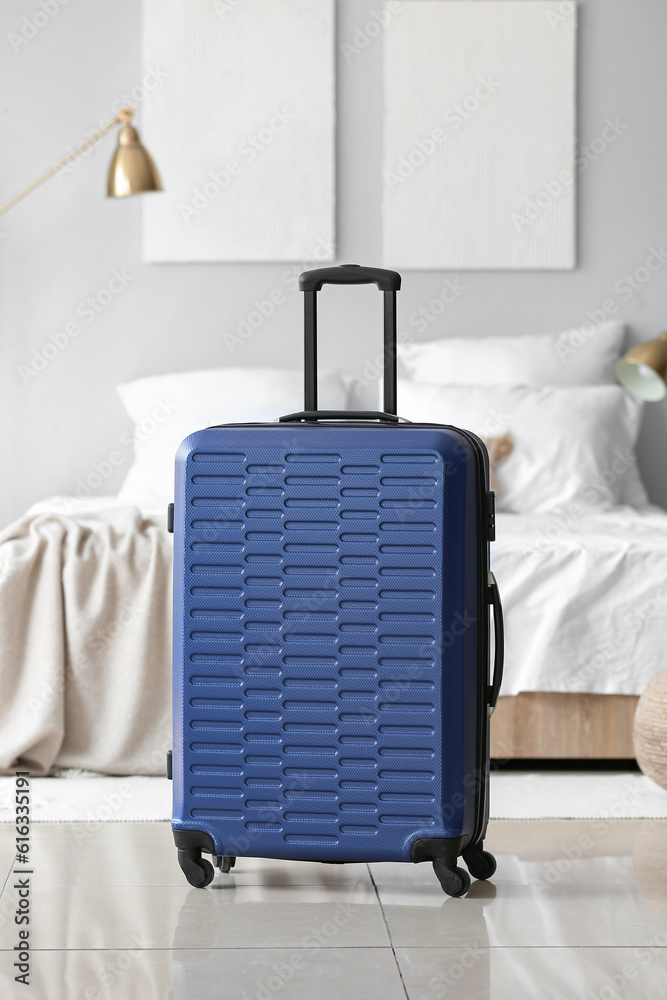 Blue suitcase in light bedroom