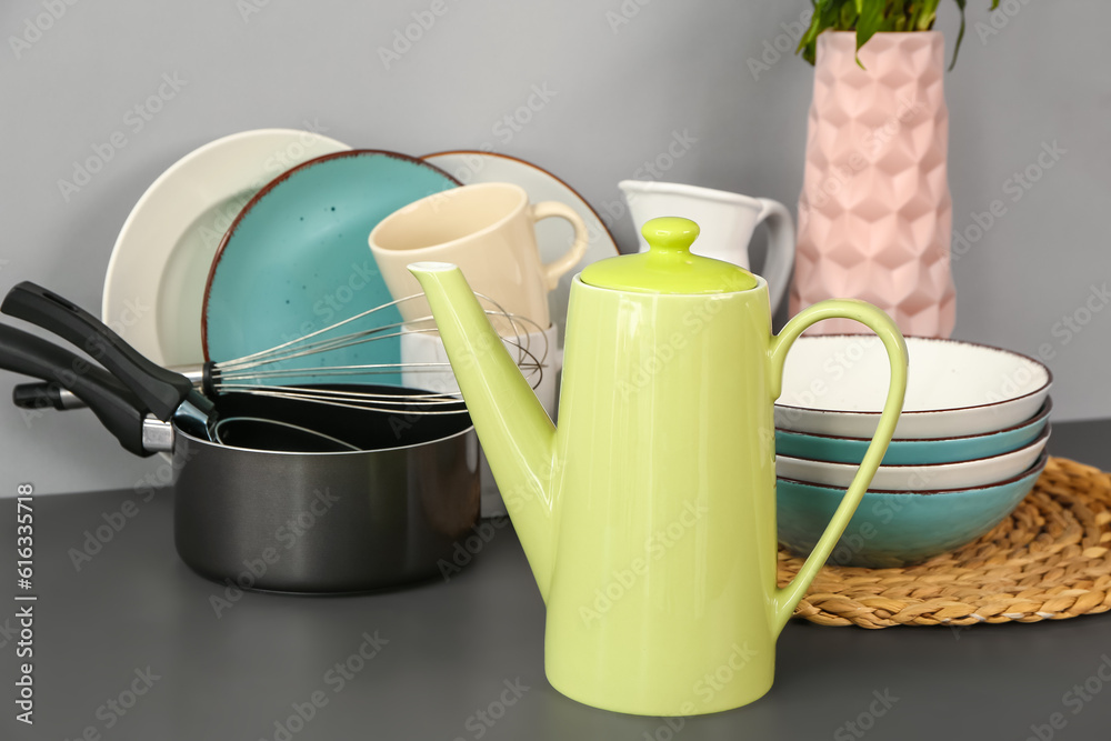 Composition with teapot and different kitchen stuff on black table