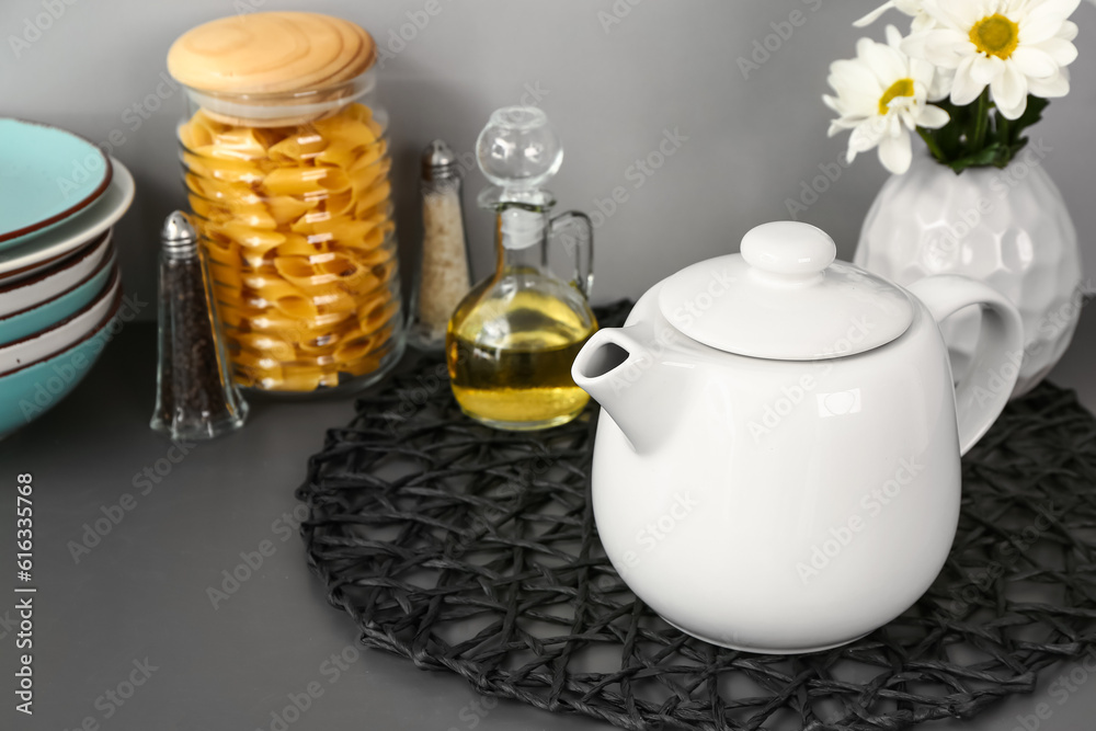 Teapot with flowers and different kitchen stuff on black table