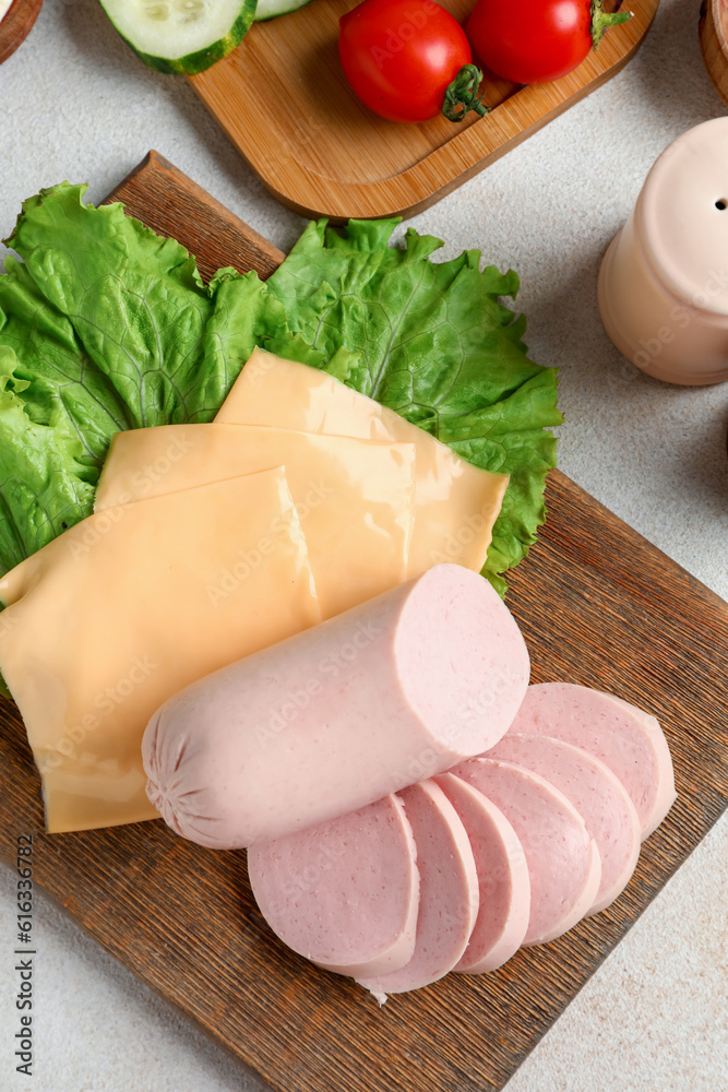 Wooden board with tasty boiled sausage and cheese on light background