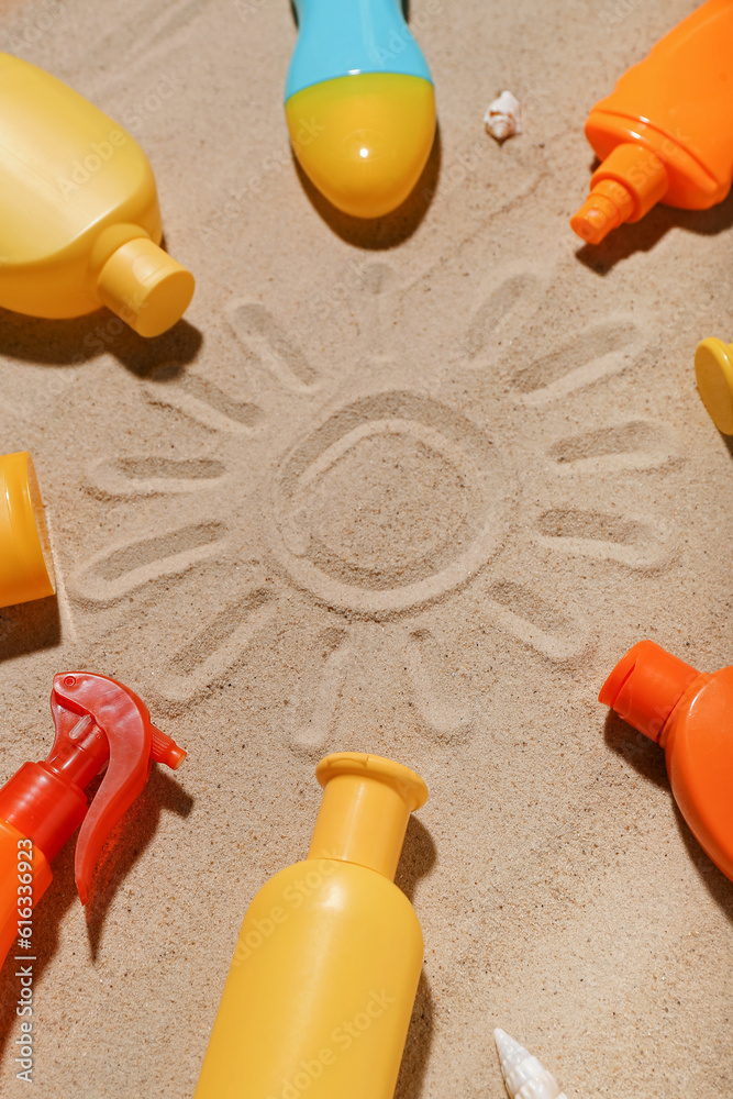 Creative composition with frame made of different sunscreen creams on sand