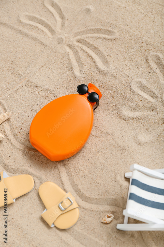 Creative composition with sunscreen cream and beach accessories on sand