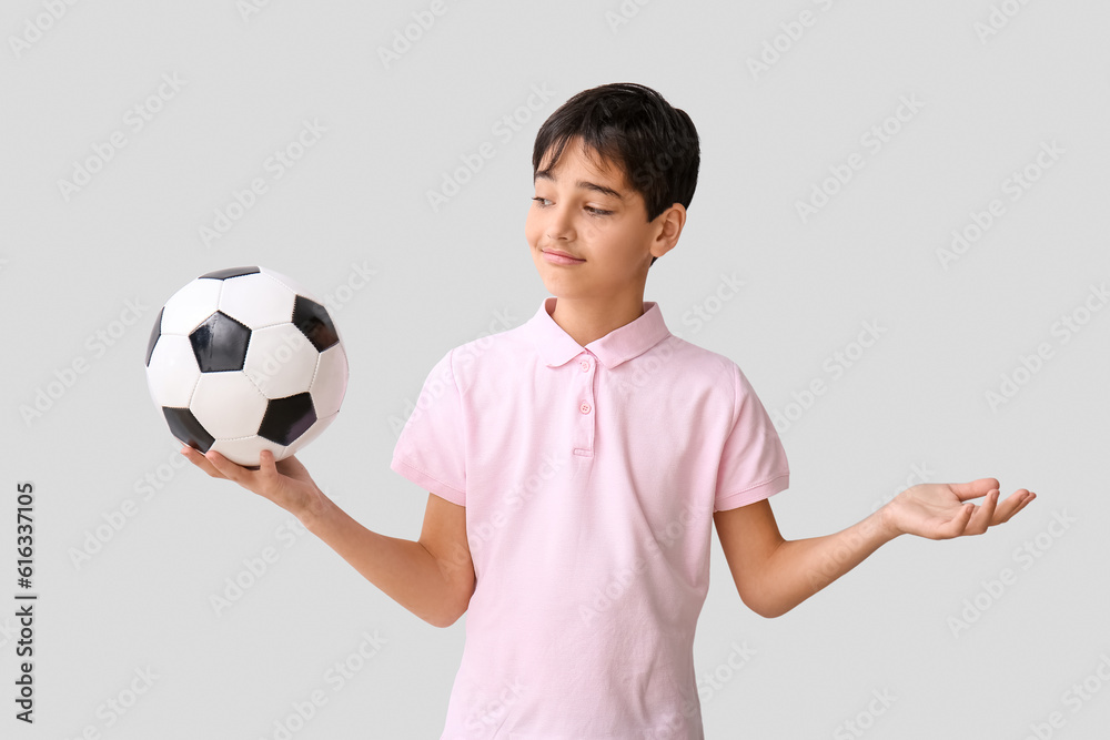 Little boy with soccer ball on grey background