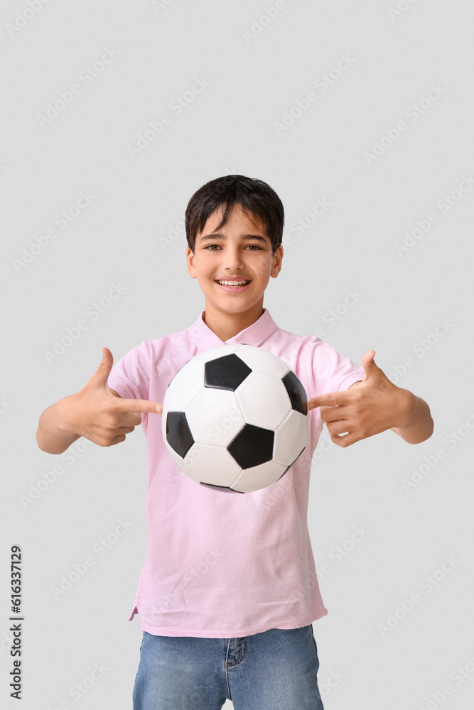 Little boy with soccer ball on grey background