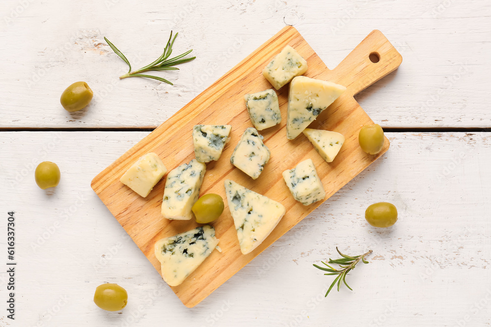 Board with pieces of tasty cheese on light wooden background