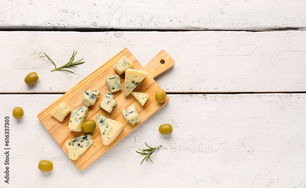 Board with pieces of tasty cheese on light wooden background