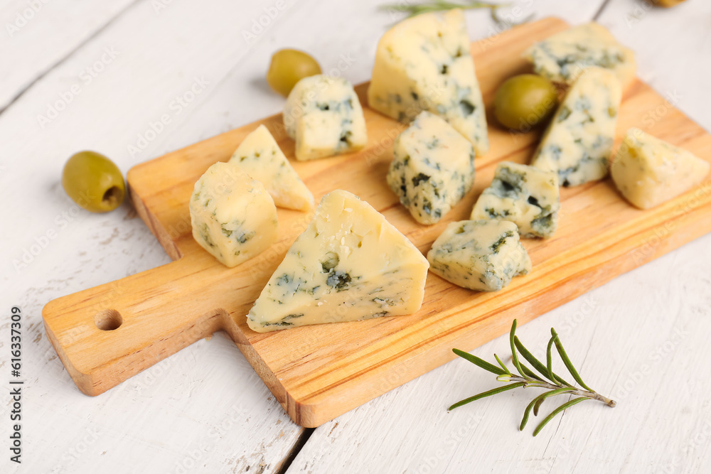 Board with pieces of tasty cheese on light wooden background