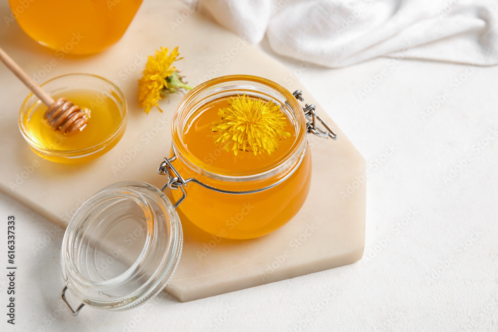 Board, jars and bowl with dandelion honey on white background