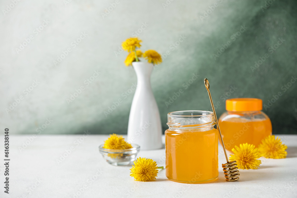 Jars with dandelion honey on white table