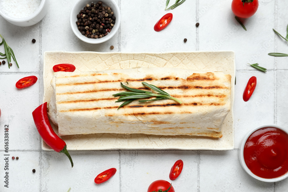 Plate of tasty shawarma with rosemary and chilli on white tile table