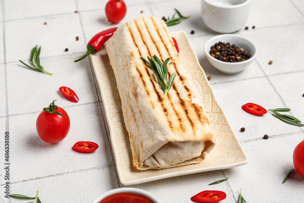 Plate of tasty shawarma with rosemary and chilli on white tile table