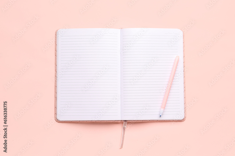 Blank open notebook with pen on pink background