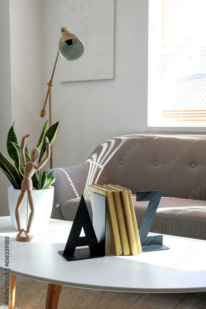 Bookend with wooden mannequin and houseplant on table in living room