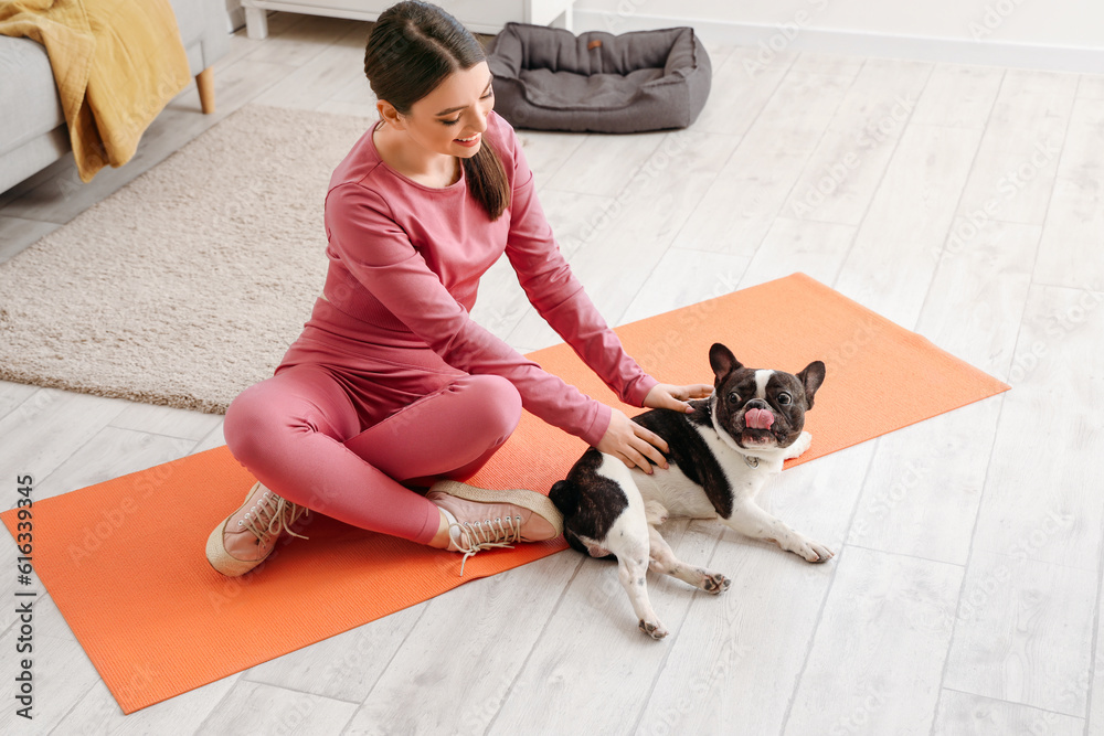 Sporty young woman with her French bulldog at home