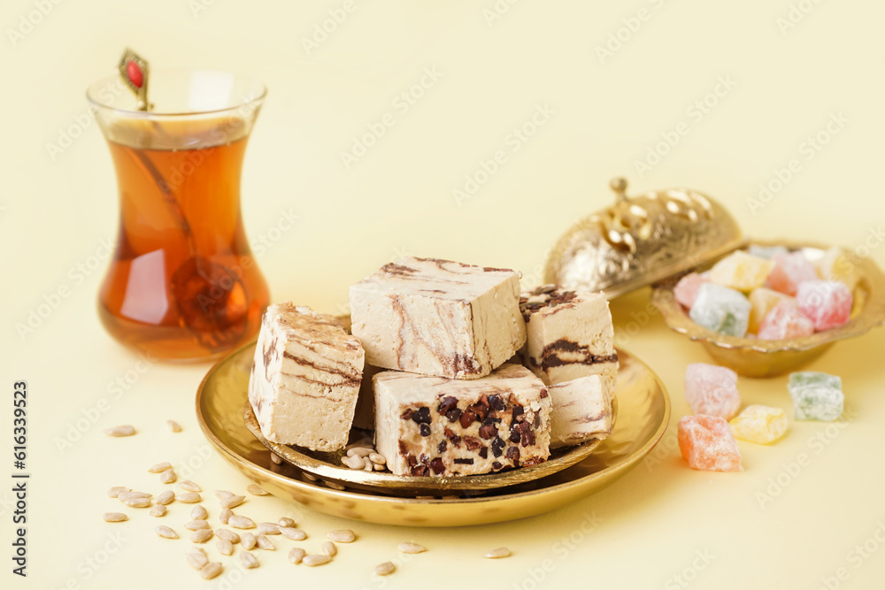 Plates with pieces of tasty marble halva on yellow background