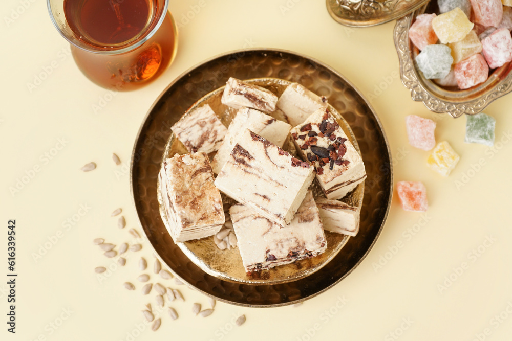 Plates with pieces of tasty marble halva on yellow background