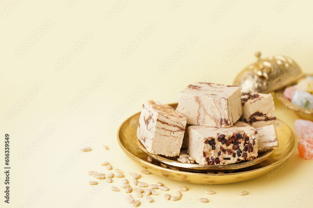 Plates with pieces of tasty marble halva on yellow background