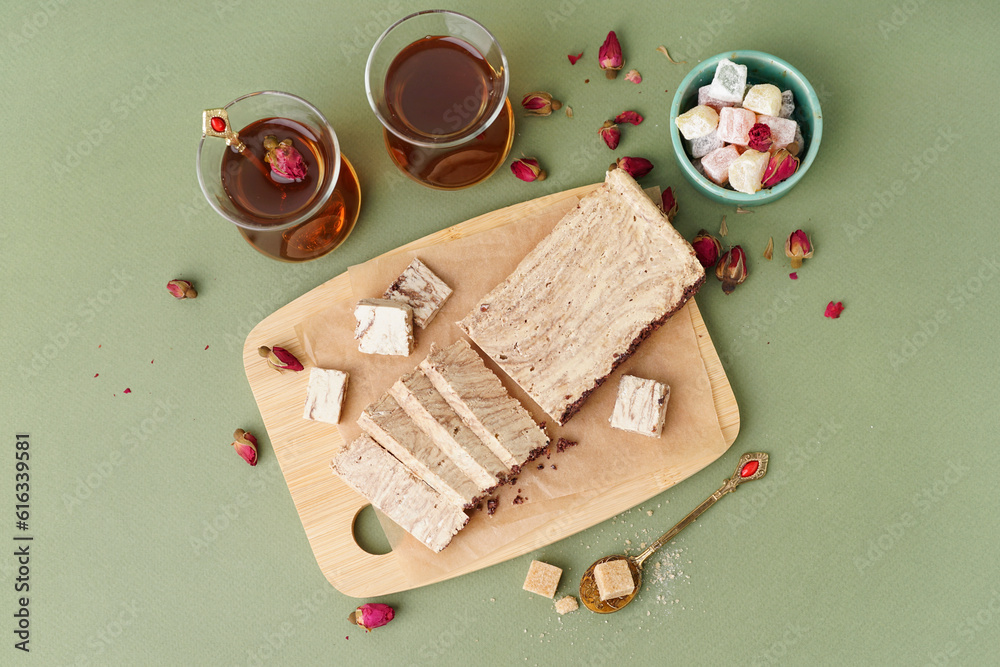 Wooden board with pieces of tasty marble halva on green background