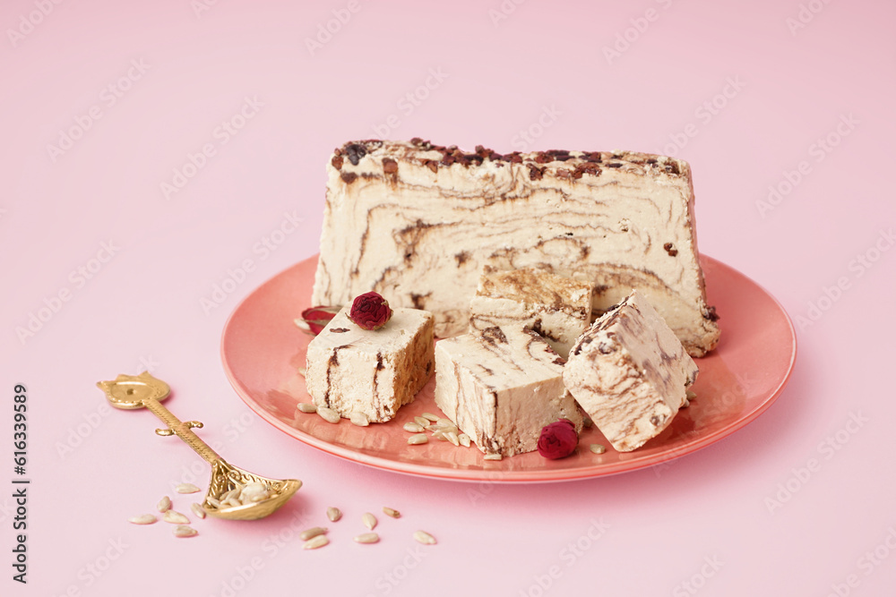 Plate with pieces of tasty marble halva on pink background